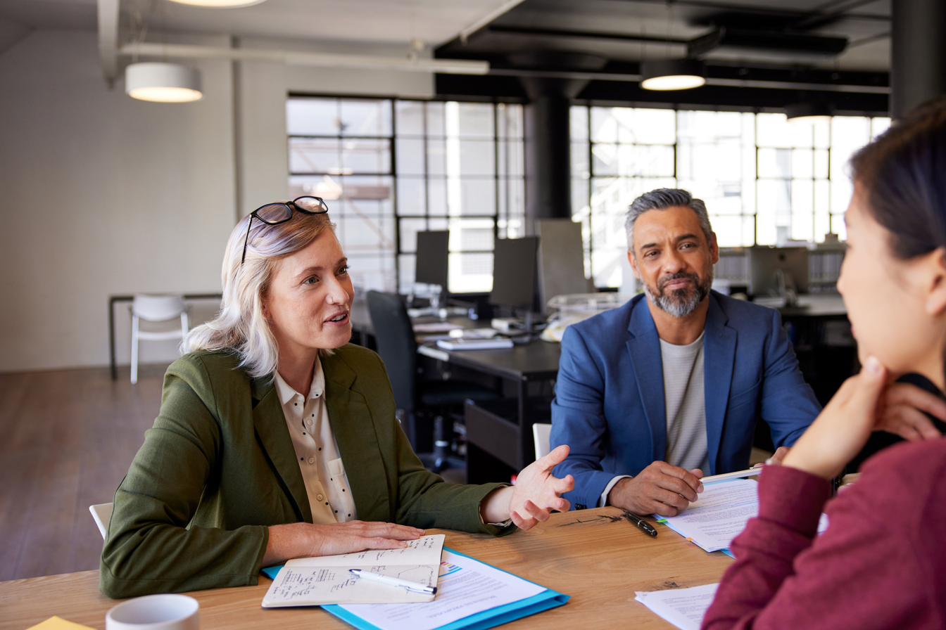 Three colleagues collaborating around a meeting table